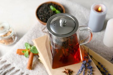 Masada kitap olan bir çaydanlık sıcak çay.