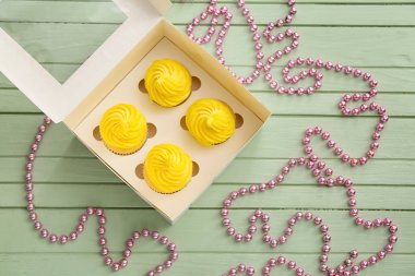 Renkli ahşap arka planda lezzetli keklerle dolu bir kutu