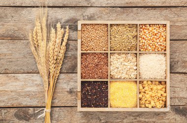 Tahta arka planda farklı tahıl gevrekleri olan kutu