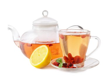 Beyaz zemin üzerinde goji çayı olan bir fincan ve çaydanlık.