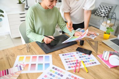 Kadın tasarımcı ve meslektaşı ofiste çalışıyor.