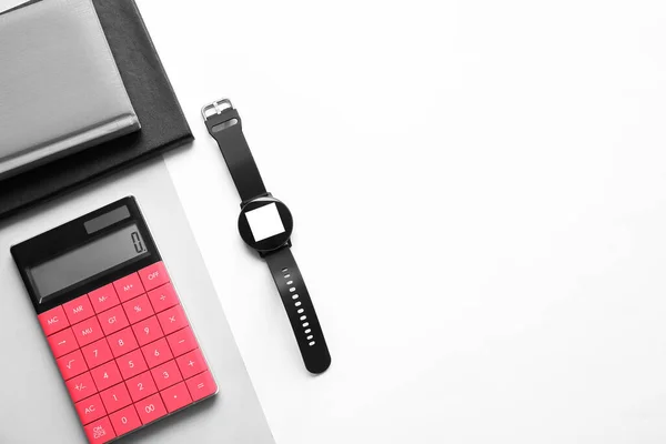 Modern smart watch with notebooks and calculator on light background