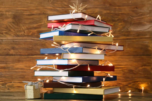 Stack of books and lights on wooden background