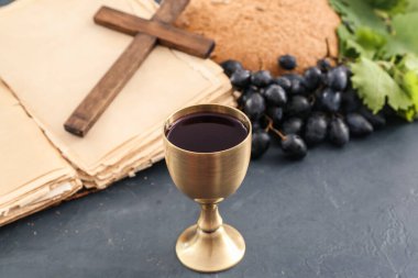 Şarap kadehi, kutsal kitap ve koyu arkaplanda haç.