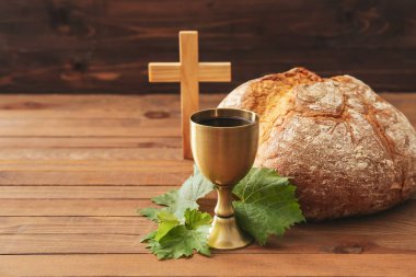 Ekmekli şarap kadehi ve ahşap zemin üzerinde haç.