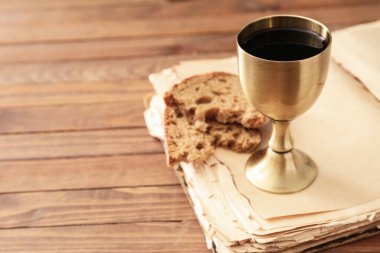 Kutsal İncil, ekmek ve şarap kadehiyle ahşap arka planda