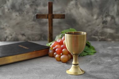 Haçlı şarap kadehi ve grunge arka planda kutsal İncil.