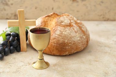 Ekmekli şarap kadehi ve gri arka planda haç.