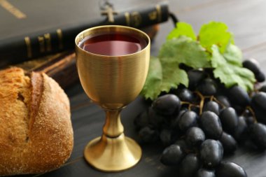 Ekmekli şarap kadehi ve koyu ahşap arka planda İncil.