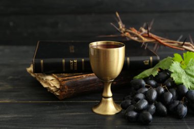 Kutsal İncil 'li şarap kadehi ve koyu ahşap arka planda dikenli taç.