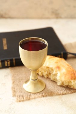 Ekmekli şarap kadehi ve gri arka planda İncil.