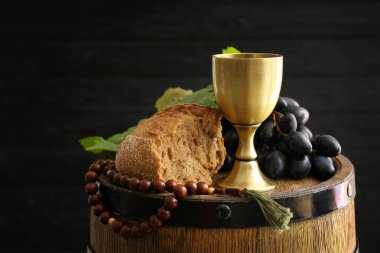 Koyu arkaplanda boncuk ve ekmek dolu bir kadeh şarap.