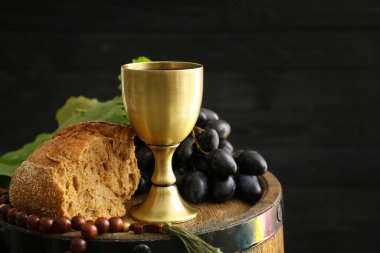 Koyu arkaplanda boncuk ve ekmek dolu bir kadeh şarap.