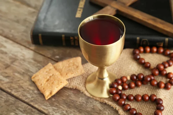 Chalice of wine with bread, beads and Holy Bible on table