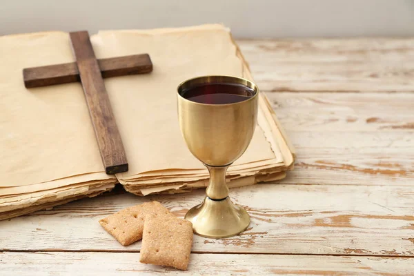 Chalice of wine, bread, Holy Bible and cross on white wooden background