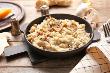 Ahşap arka planda lezzetli risotto ile kızartma tavası.
