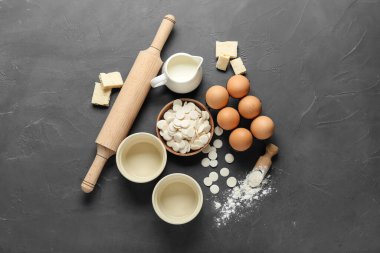 Koyu arkaplanda çikolata damlaları ve fırın malzemeleri var.