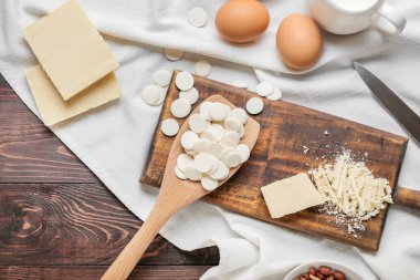 Çikolata damlalı kaşık ve ahşap arka planda fırın malzemeleri.