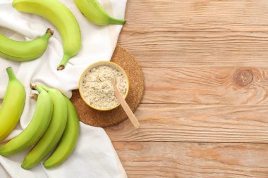 Ahşap zemin üzerinde muz unu olan kase ve kaşık.
