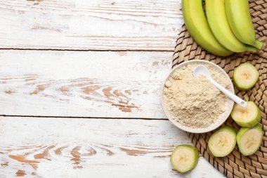 Ahşap zemin üzerinde muz unu olan bir kase