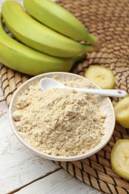 Ahşap zemin üzerinde muz unu olan bir kase