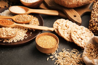 Koyu arkaplanda farklı tahıllar ve taze ekmekler, yakın plan.