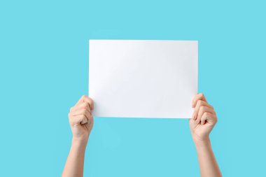 Renk arkaplanı üzerinde boş kağıt sayfası olan kadın elleri