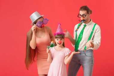 Renkli arka planda tuhaf kılık değiştirmiş genç bir aile. 1 Nisan şakası