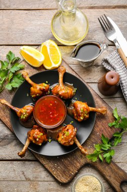 Lezzetli tavuklu lolipoplar ve ahşap arka planda sos.