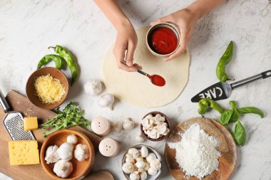 Kadın arka planda pizza yapıyor.