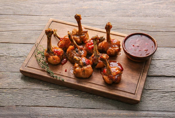 Board with tasty chicken lollipops on wooden background