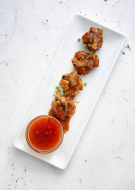 Lezzetli tavuk lolipopları ve hafif arkaplanlı sos tabağı.