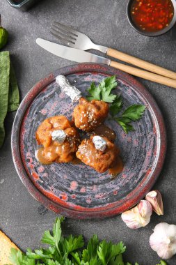 Koyu arkaplanda lezzetli tavuk lolipopları olan bir tabak.