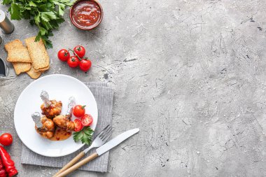 Lezzetli tavuklu lolipoplar ve gri arka planda domatesler.