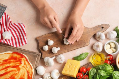 Kadın arka planda pizza yapıyor.