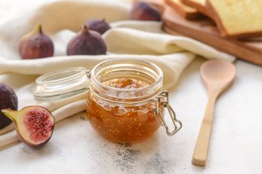 Glass jar with sweet fig jam on grunge background
