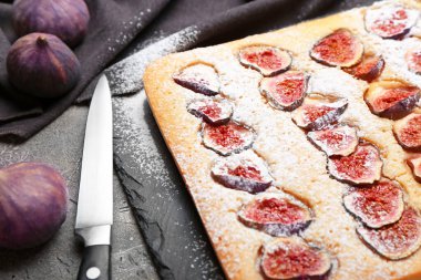 Board with delicious fig pie on grunge background