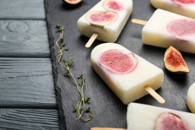 Board with delicious fig ice-cream on dark wooden background