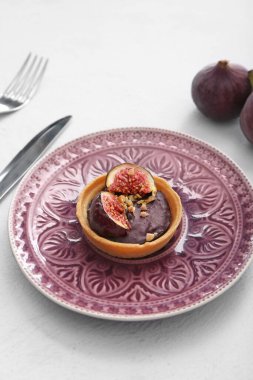 Tartlet with tasty chocolate and figs on light background