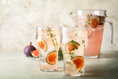 Glasses of tasty fig lemonade on grunge background