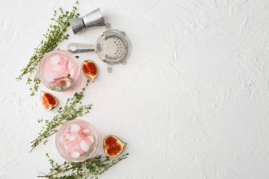 Glasses of tasty fig lemonade on light background
