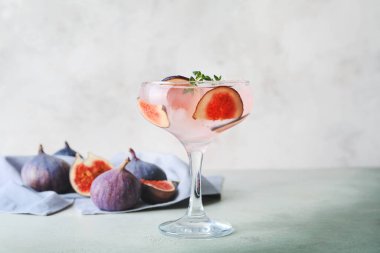 Glass of tasty fig lemonade on table