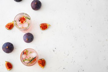 Glasses of tasty fig lemonade on light background