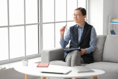 Ofisteki kanepede oturan kadın psikolog portresi.