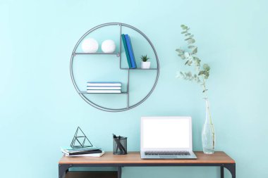 Stylish workplace with modern laptop against color wall in room