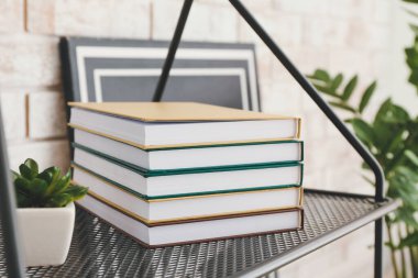 Stack of books on table against brick wall