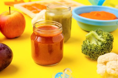 Jars with different baby food and ingredients on color background, closeup