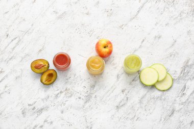 Jars with different baby food and ingredients on light background