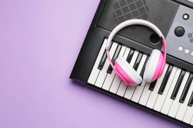 Modern synthesizer and headphones on color background, closeup