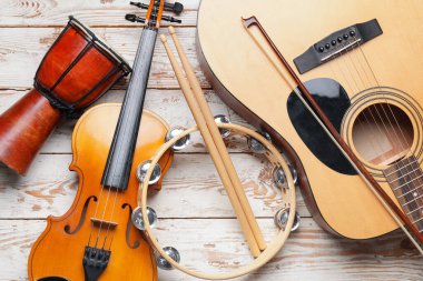 Different musical instruments on light wooden background, closeup